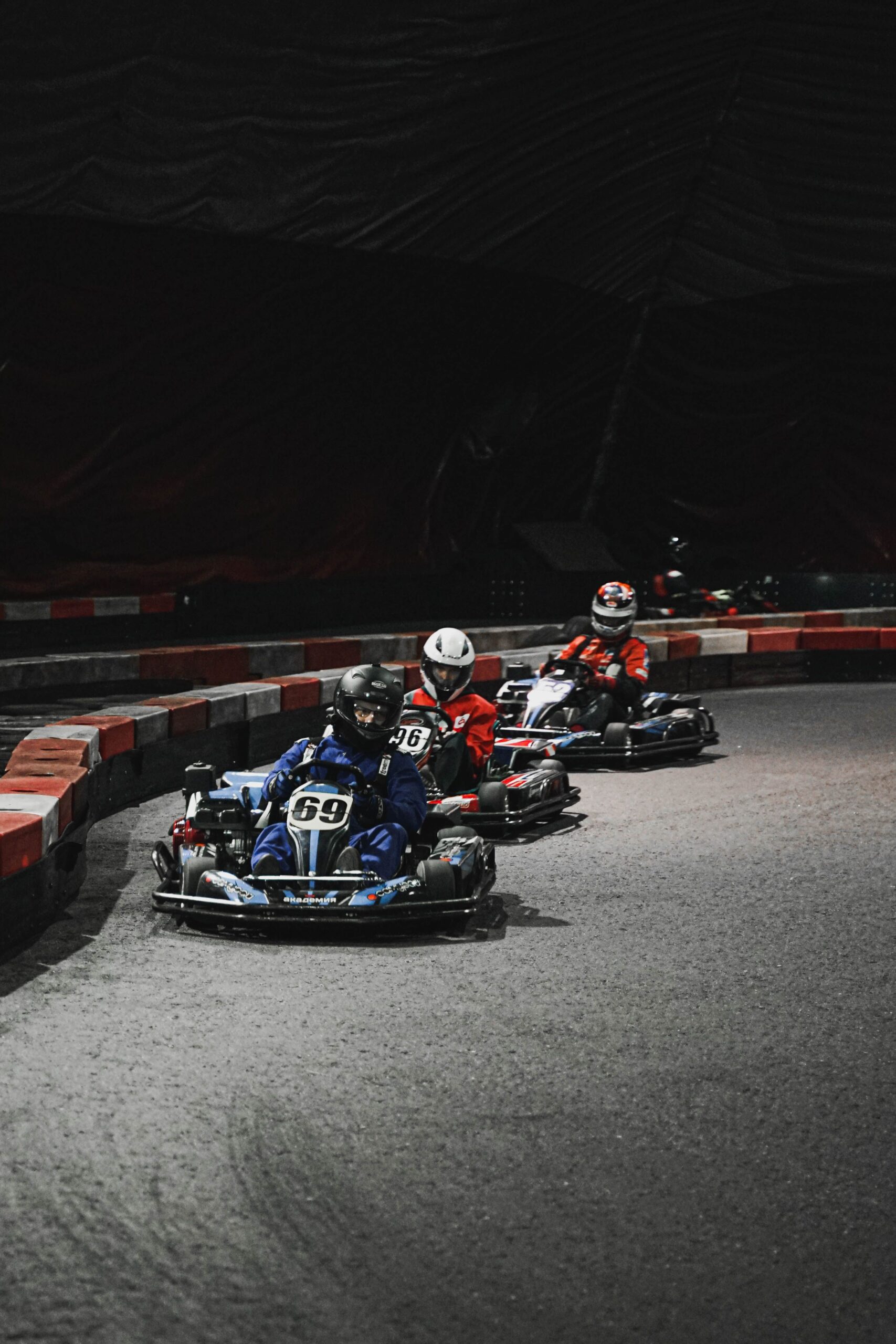Thrilling indoor go-kart race with drivers speeding through a curve.