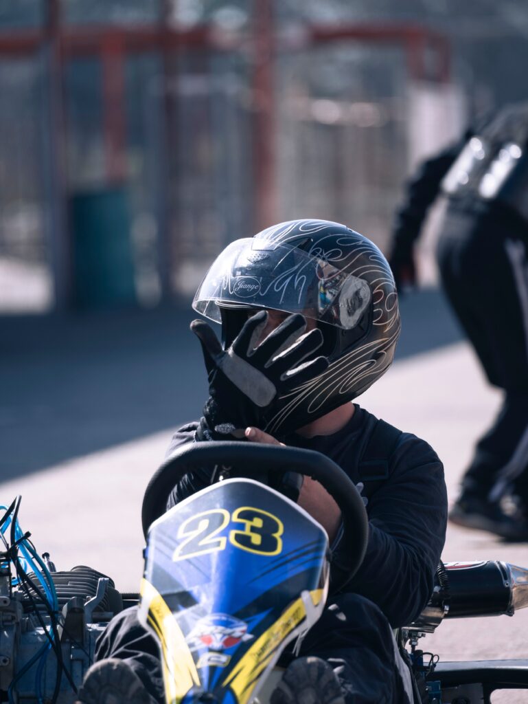 A go-kart racer in helmet poised for action on the track, showcasing motorsport enthusiasm.